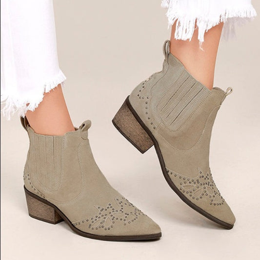 A person wearing trendy taupe Matisse Women's X Amuse Society Backstage booties with stud embellishments and elastic side panels, paired with frayed white jeans.