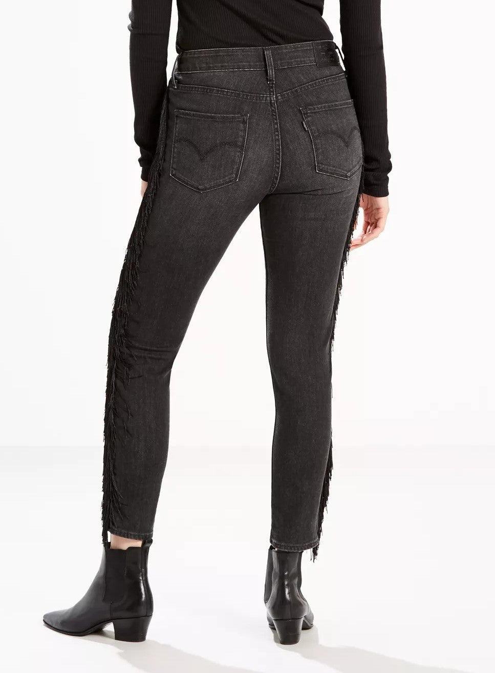 A person showcasing a pair of Levi's Limited 721 Fringe-Trim Skinny Ankle Jeans in Black and black ankle boots from Levi's Limited Collection.